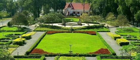 A well-maintained garden with a central lawn, surrounded by neatly trimmed hedges and flower beds.