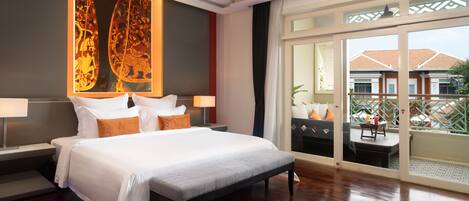 A hotel room with a large bed, two bedside tables with lamps, a large window with a view of buildings, and a decorative wall piece.