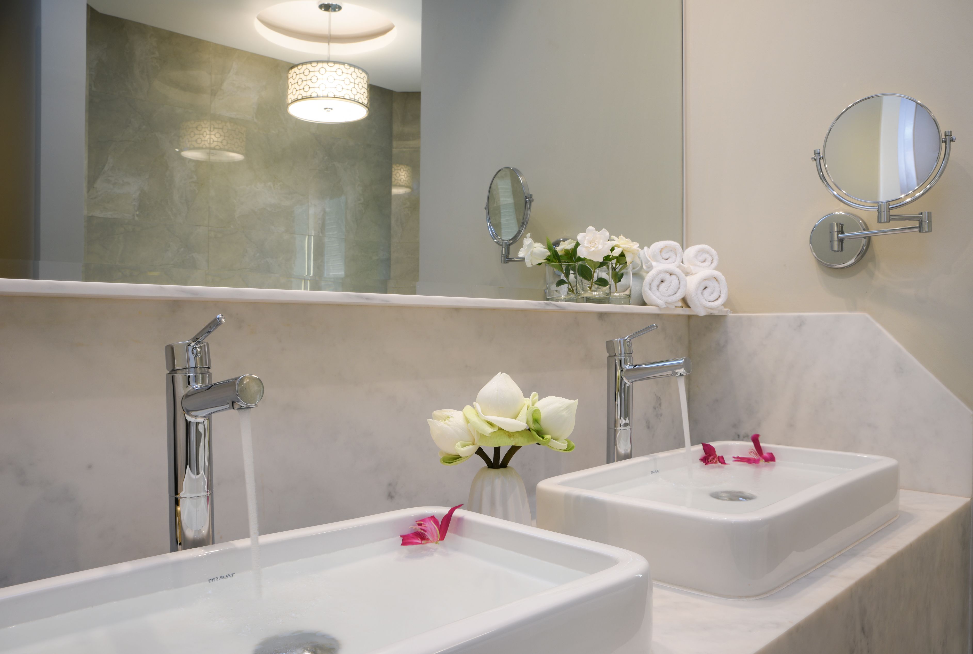 Un baño con dos lavamanos, un espejo y un florero con flores.