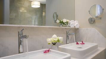 Un baño con dos lavamanos, un espejo y un florero con flores.
