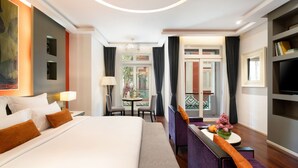 A hotel room with a large bed, a sofa, a small table with a vase, and a TV. - Memoire Palace Resort & Spa (Siem Reap)