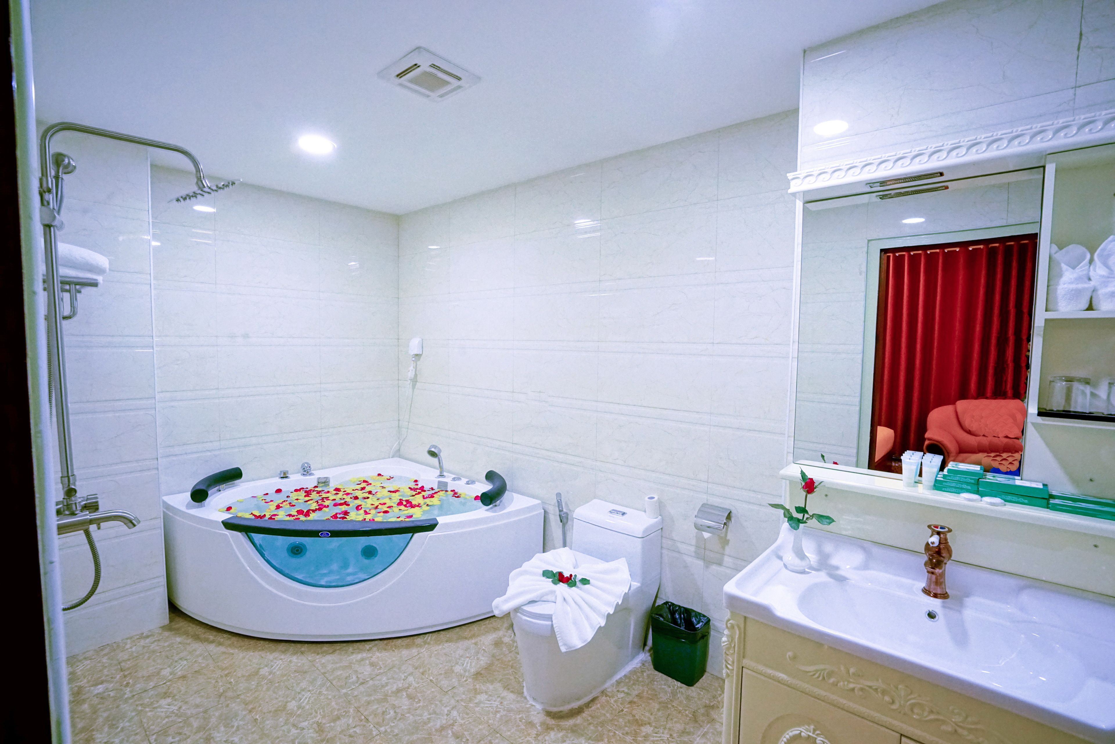 A modern bathroom with a curved bathtub, a toilet, a sink, and a shower area.