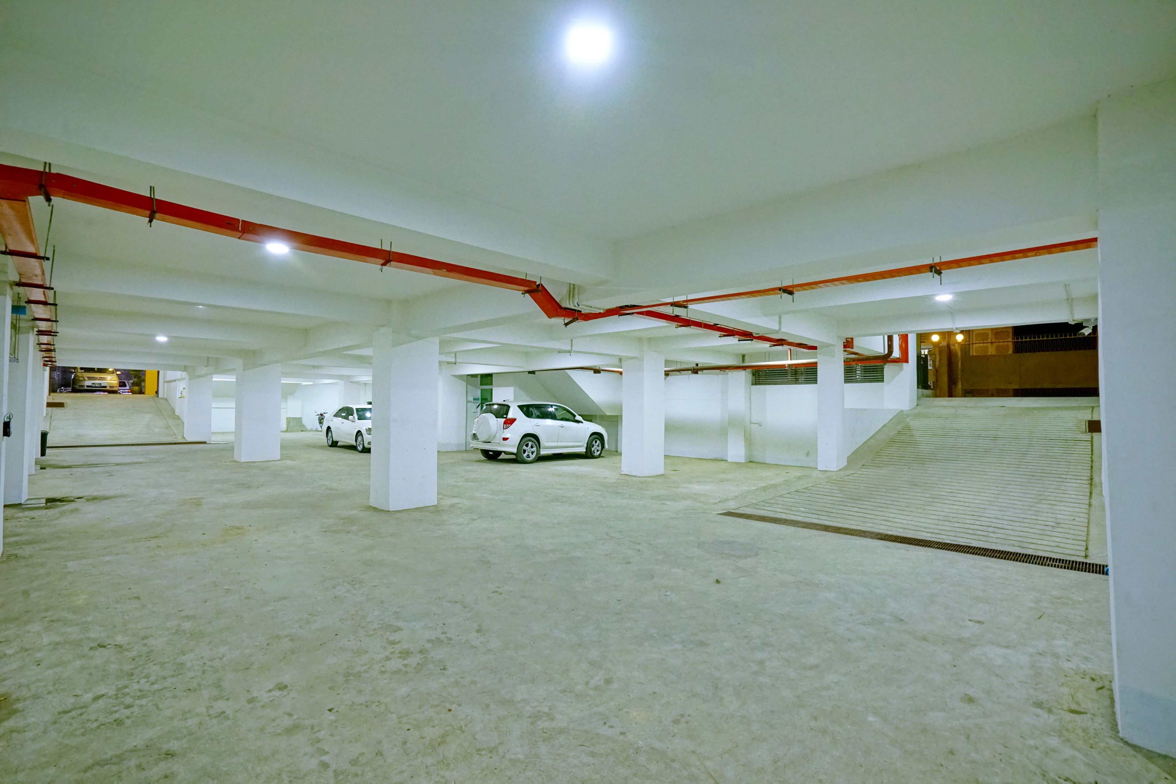 A multi-level parking garage with white pillars and red pipes.