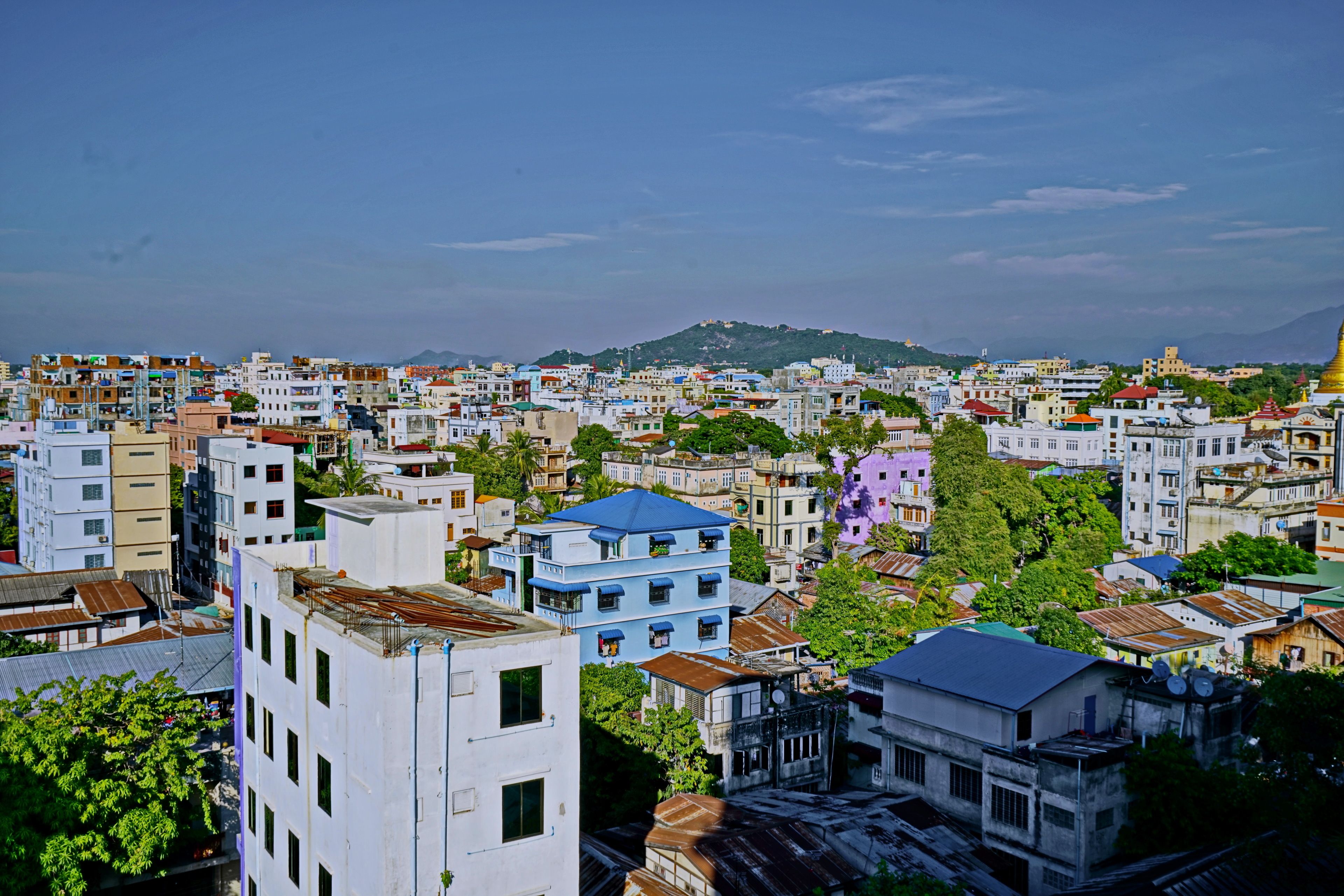 A densely packed urban area with a variety of building styles and a prominent hill in the background.