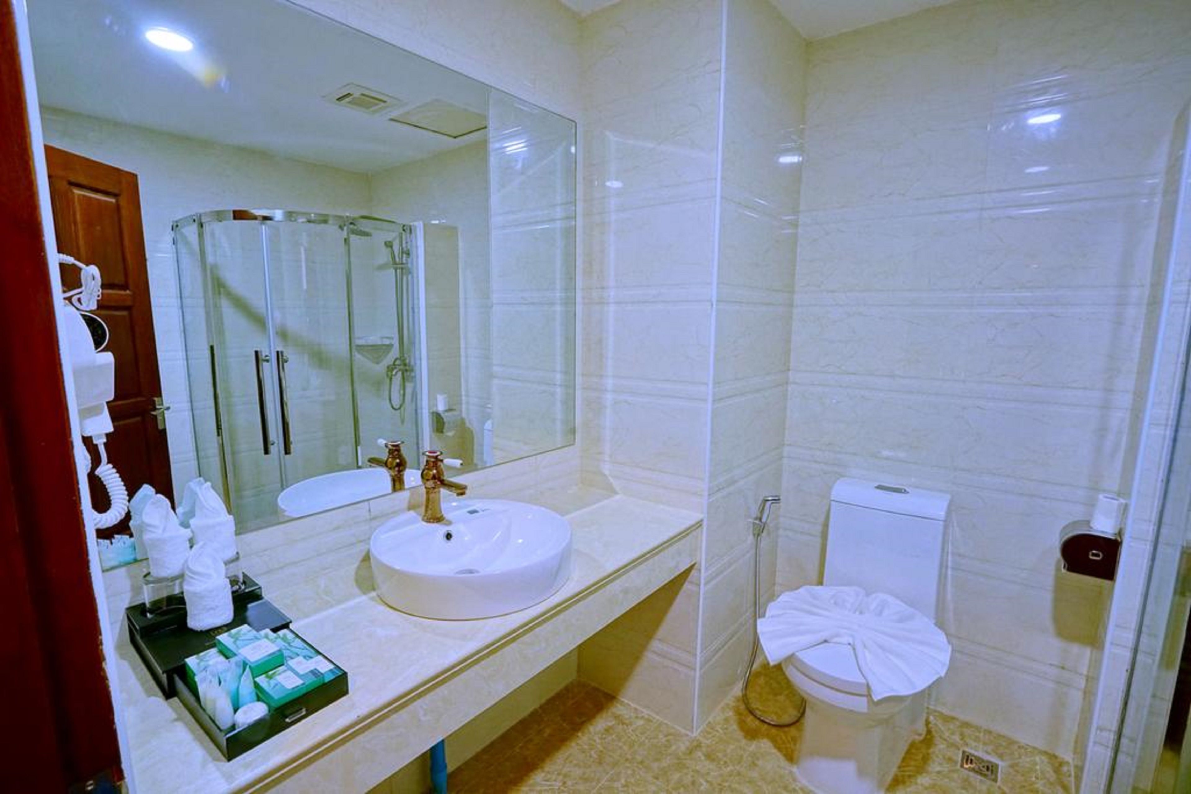 A modern bathroom with a round sink, a glass shower enclosure, and a toilet.