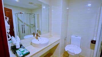A modern bathroom with a round sink, a glass shower enclosure, and a toilet.