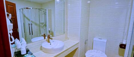 A modern bathroom with a round sink, a glass shower enclosure, and a toilet.