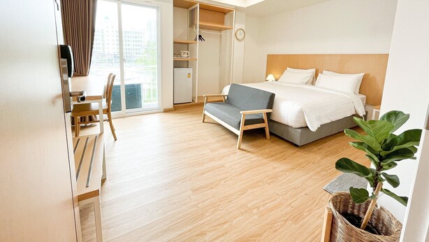Una habitación de hotel moderna con cama, sofá, escritorio y un amplio ventanal.