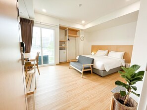 Une chambre d’hôtel moderne équipée d’un lit, d’un canapé, d’un bureau et d’une grande fenêtre.