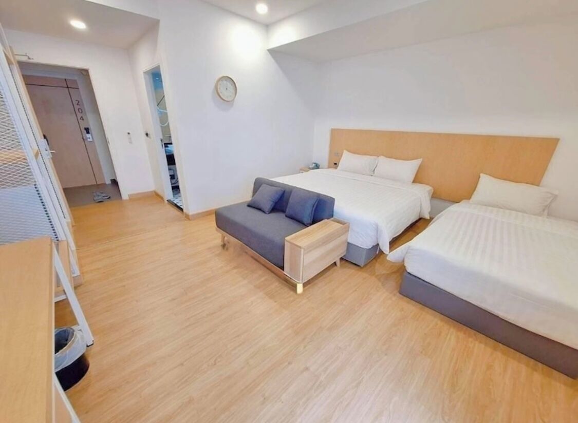 A modern hotel room with a large bed, a sofa, and a small table.