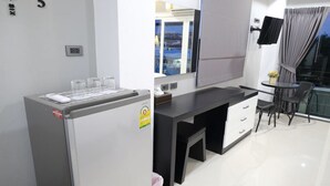 Una cocina moderna con refrigerador, una mesa de comedor con sillas y un pequeño balcón con vistas.