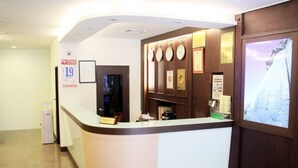 A reception desk with a clock, framed certificates, and a window with a snowy view. - Foung Kou Hotel (Magong)