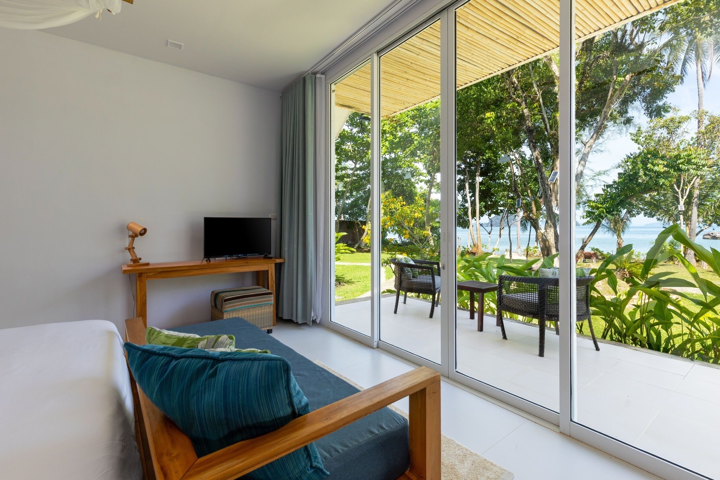 Un dormitorio con un amplio ventanal corredero que da a un patio exterior con vista al mar.