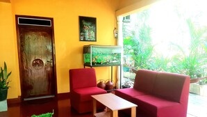 Una habitación con puerta de madera, un sofá rojo, una mesita y un acuario.