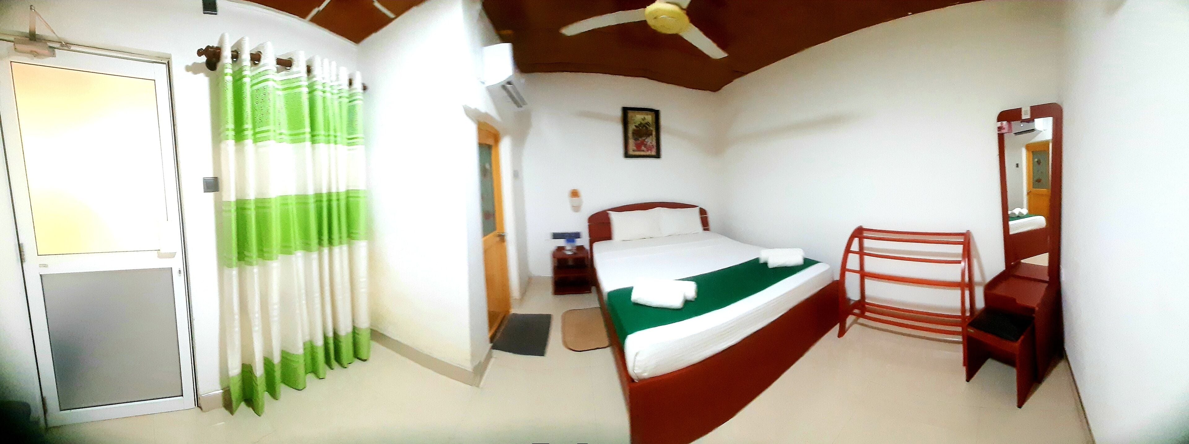 A bedroom with a bed, a chair, a desk, and a mirror.