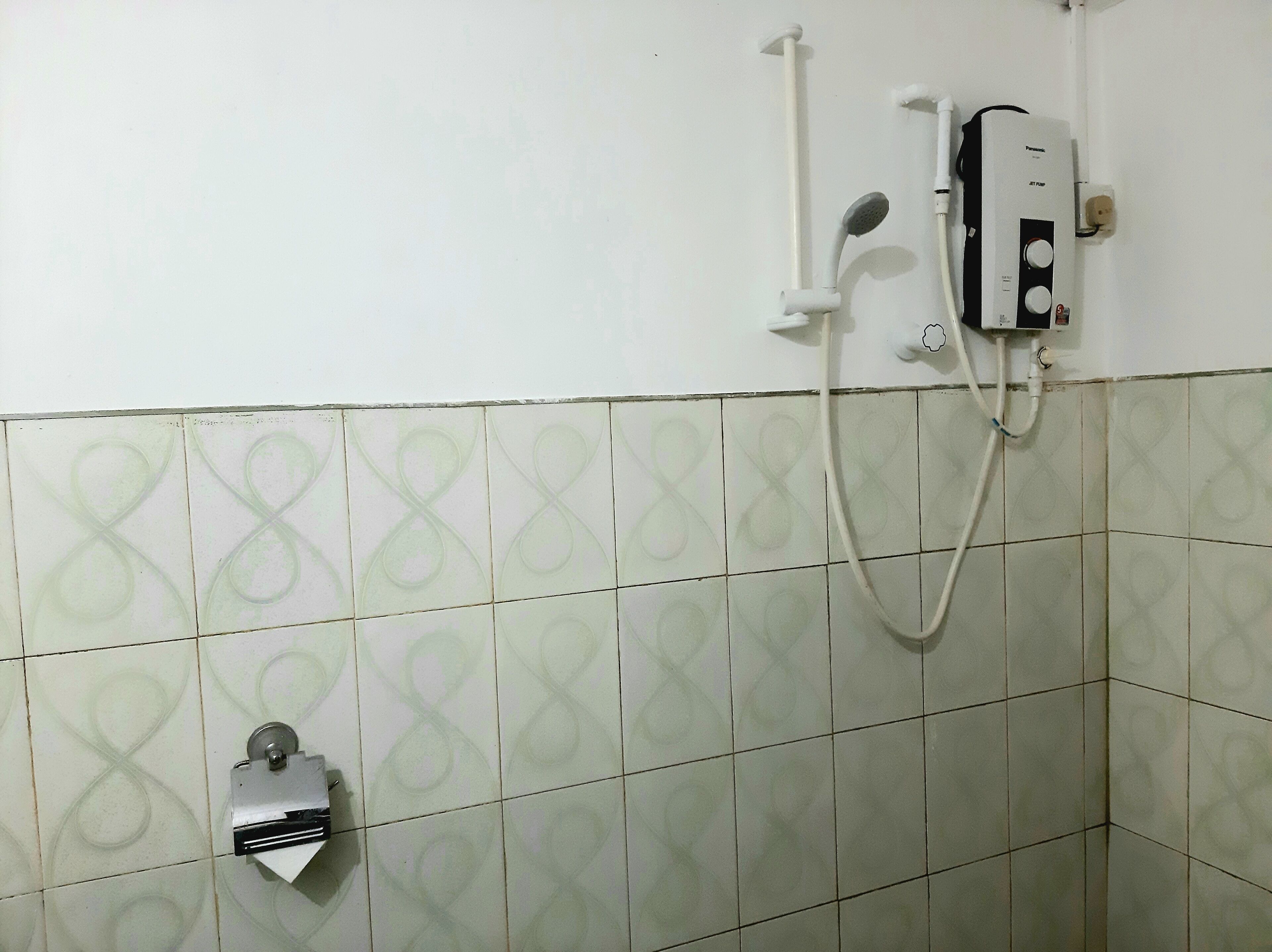 A bathroom with a shower, a toilet, and a wall-mounted heater.