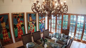 Un comedor con candelabro, pinturas coloridas y vistas amplias a través de grandes ventanales.