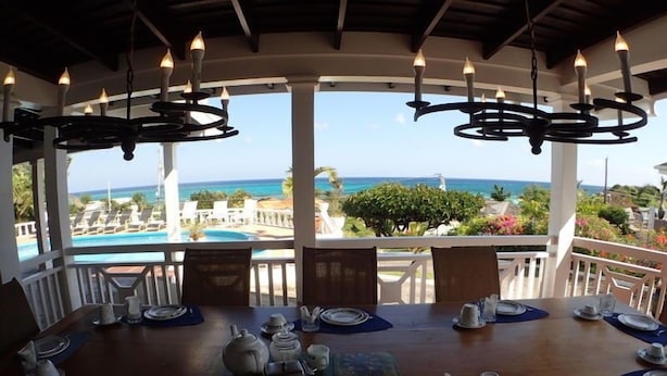 Comedor con una mesa dispuesta para cuatro personas, con vistas a una piscina y al océano.