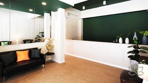A modern reception area with a black leather sofa, a small side table, and a green wall. - Buakham Rim Khong (Chiang Saen)