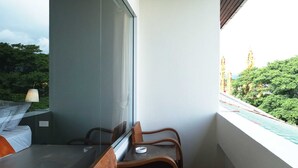 A balcony with a dining table and chairs, a window, and a view of greenery. - Buakham Rim Khong (Chiang Saen)