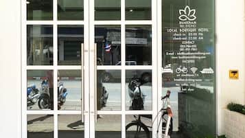 A hotel entrance with a glass door reflecting parked motorcycles and a bicycle.