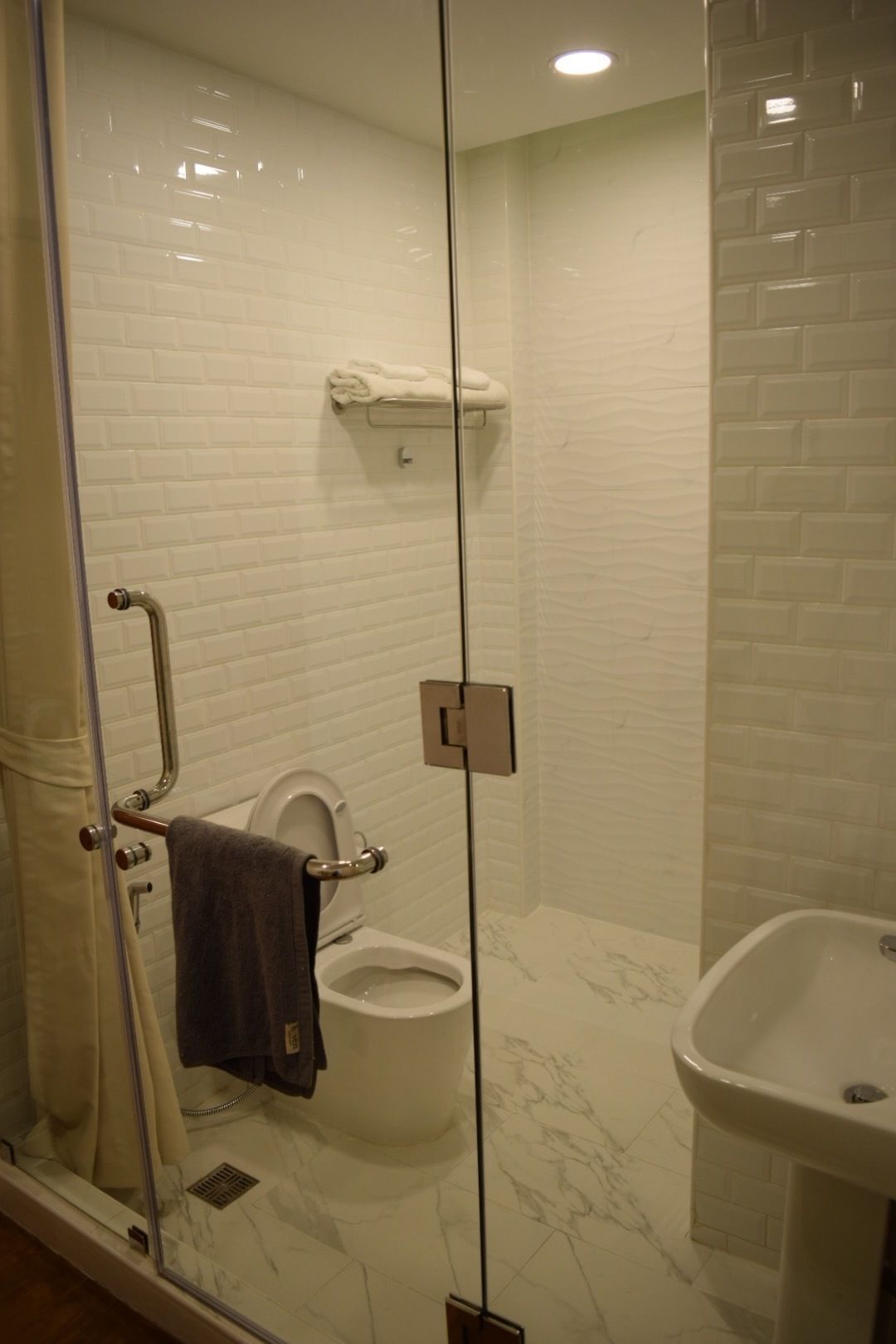 Un bagno moderno con cabina doccia in vetro, un water e un lavandino.
