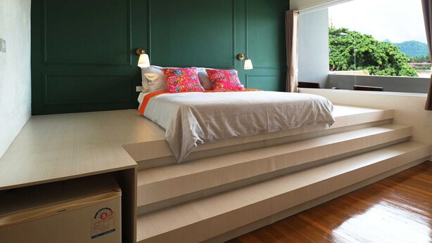 A bedroom with a bed, a desk, and a window with a view of greenery. - Buakham Rim Khong (Chiang Saen)