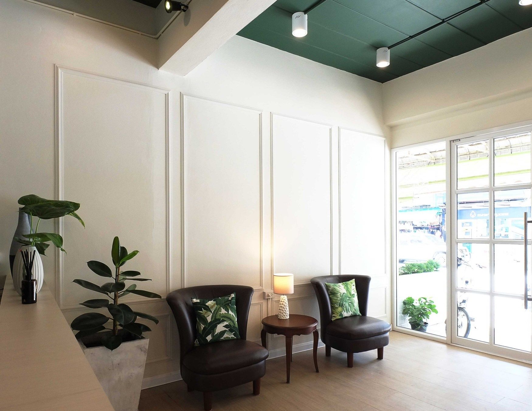 A modern interior with two leather armchairs, a small table, and potted plants.