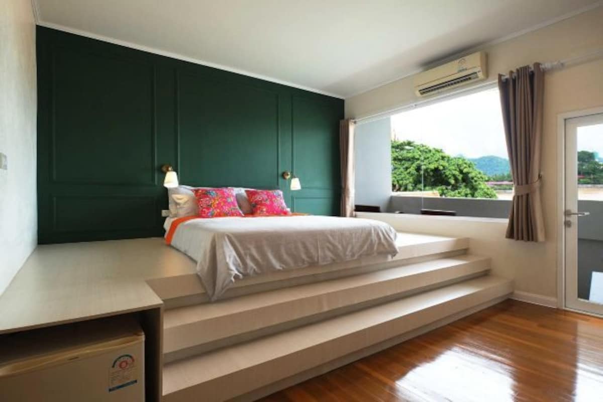 A bedroom with a bed, a window with a view, and a staircase.