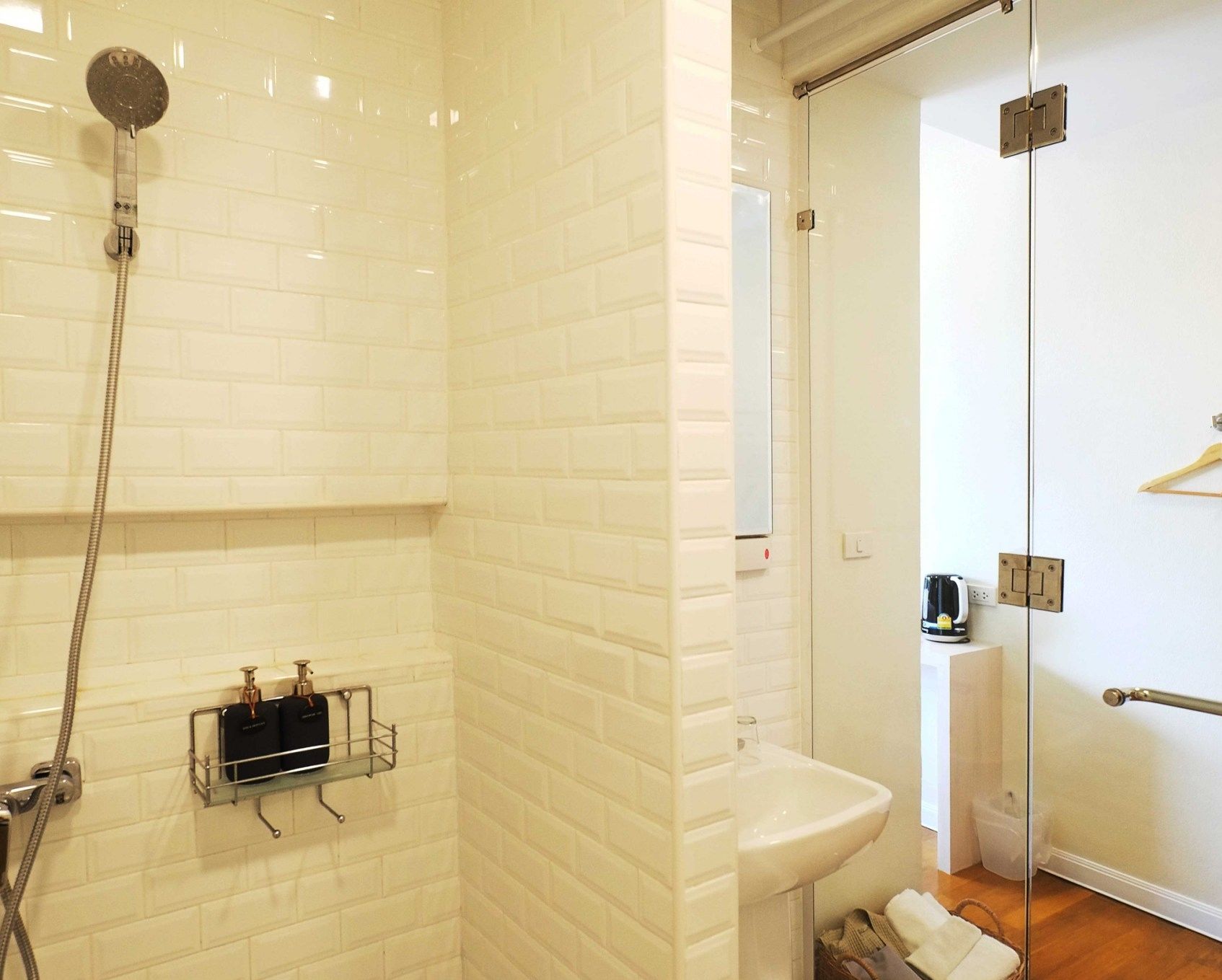 A modern bathroom with a glass shower enclosure, a white sink, and a towel rack.
