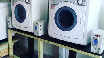 Two white washing machines on a wooden table with a black top.