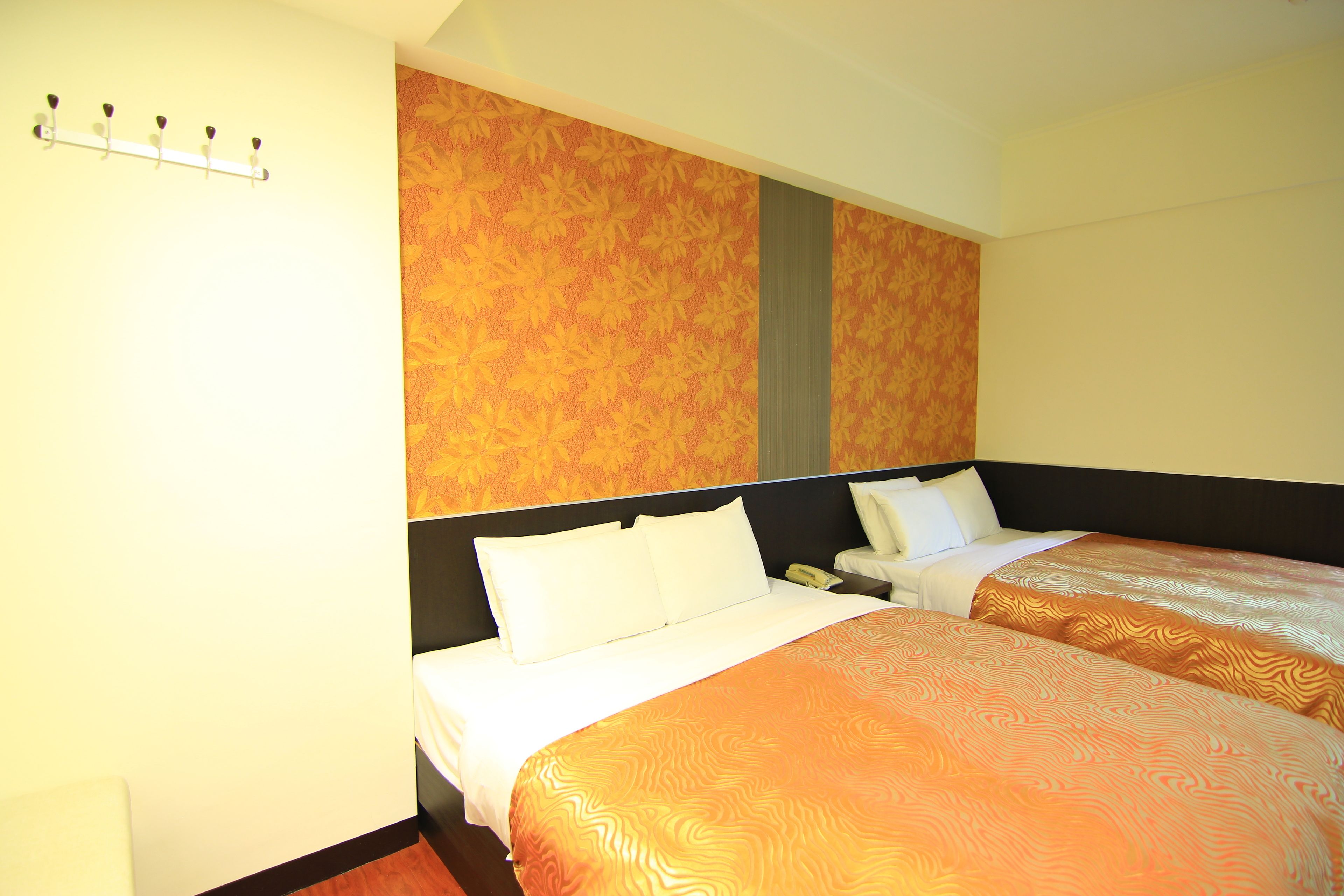 Habitación de hotel con dos camas, suelo de madera y pared con estampado.
