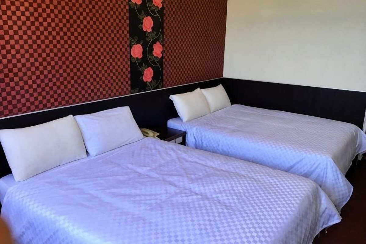 Two twin beds with white bedding, a checkered wall pattern, and a floral design on the wall.