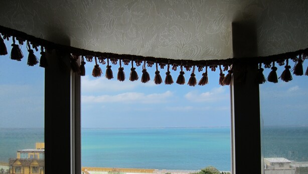 A view from a window with a view of the sea and buildings in the distance.