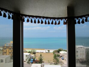 A view from a window with a view of the sea and buildings in the distance. - Penghu An-I Hotel (Magong)