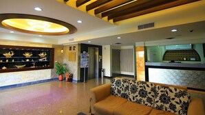 A lobby with a reception desk, a sofa, a chandelier, and a display of model boats.