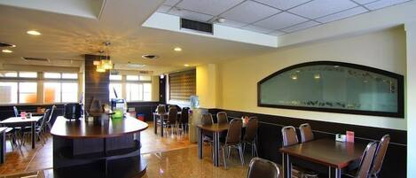 Um restaurante espaçoso com um balcão central, várias mesas de jantar e um grande painel de vidro com design decorativo.