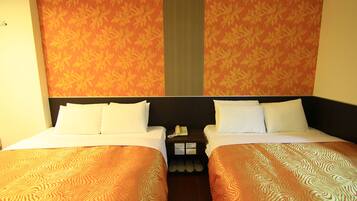 Une chambre d’hôtel avec deux lits, une table de chevet avec un téléphone et un mur décoré d’un motif.