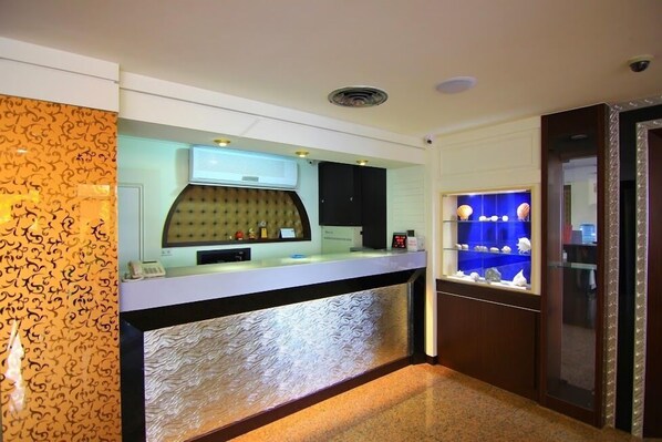 A reception area with a counter, a decorative wall, and a display case with shells. - Penghu An-I Hotel (Magong)