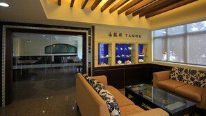 A lobby with a reception desk, a glass display case with items, and seating areas.
