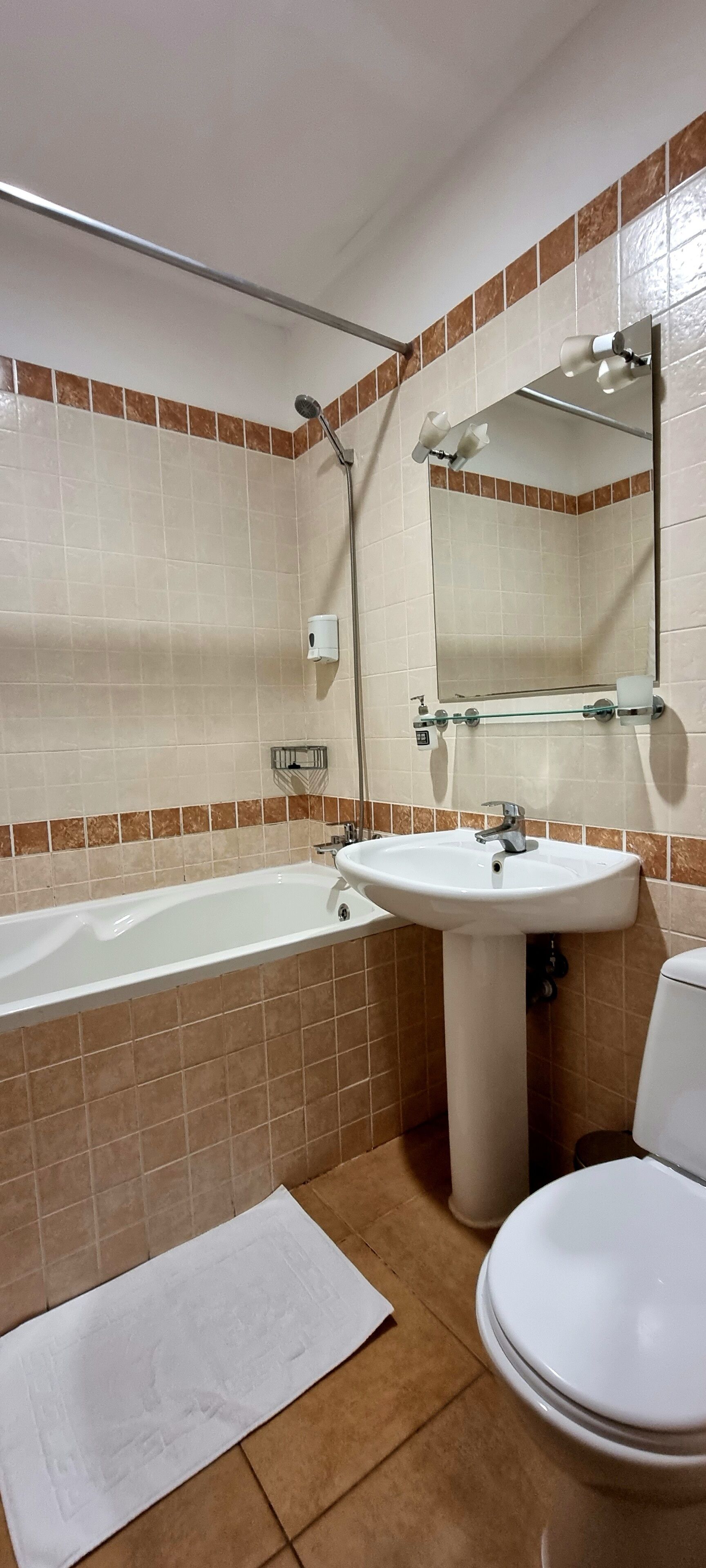 A bathroom with a bathtub, sink, toilet, and a large mirror.