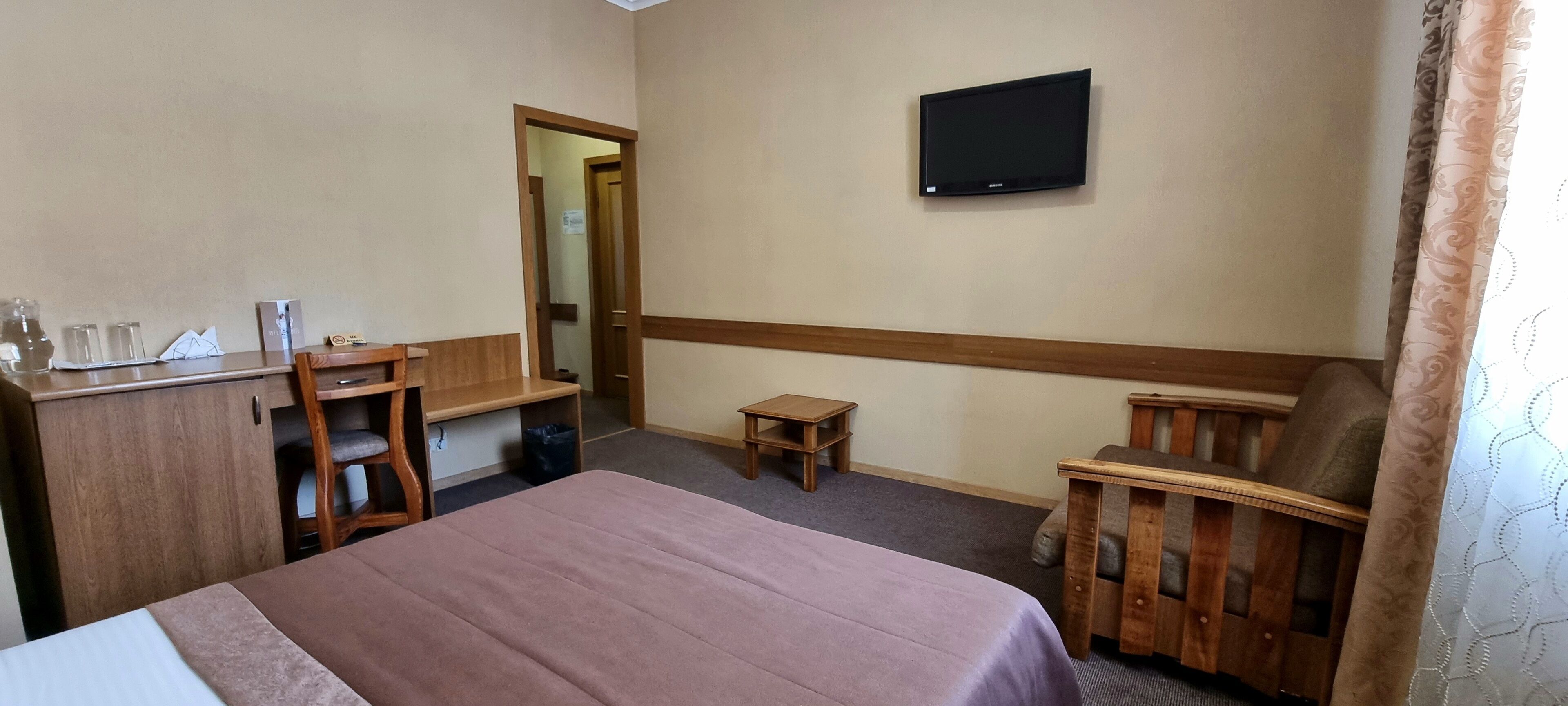 Una habitación de hotel con una cama, un escritorio, una silla, un televisor y una pequeña mesa.
