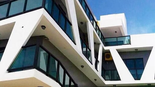 A modern multi-story building with a unique angular design, featuring large windows and a flat roof. - Penghu Noah's Ark (Huxi)