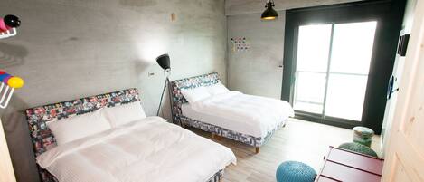 A room with two beds, a wooden floor, a large window, and a red dresser.