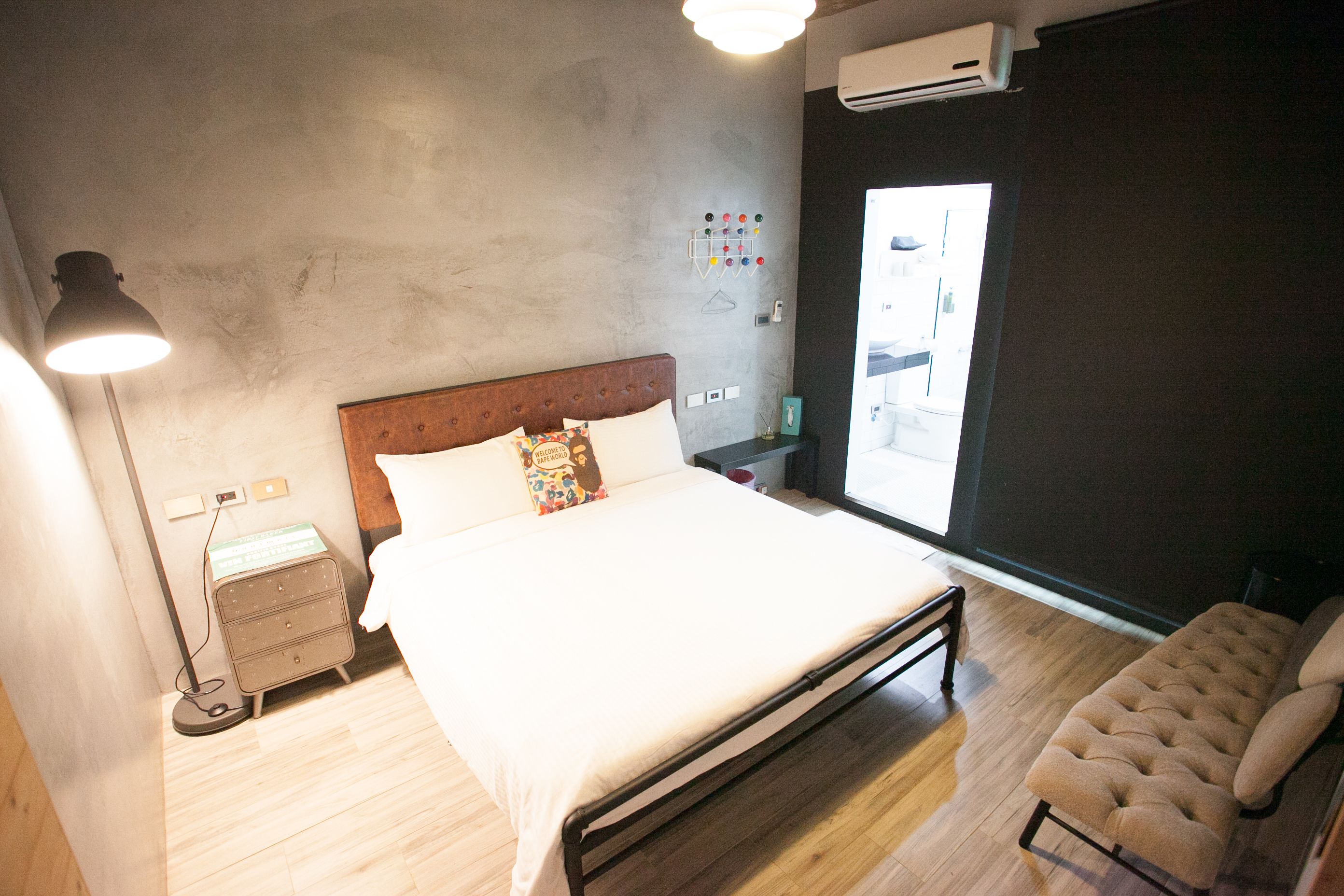 A bedroom with a bed, bedside table, lamp, and a window with a view.