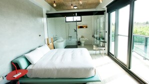 A modern bedroom with a large bed, a red side table, and a view of the balcony. - Penghu Noah's Ark (Huxi)