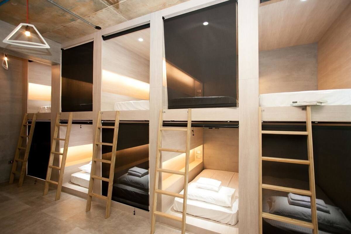 A room with bunk beds, wooden ladders, and a hanging light fixture.