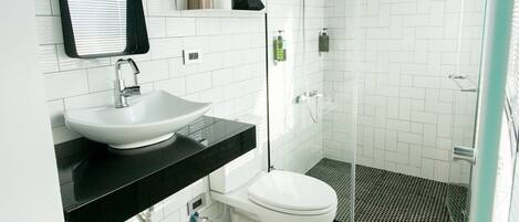 A modern bathroom with a white sink, black countertop, and a glass shower enclosure.