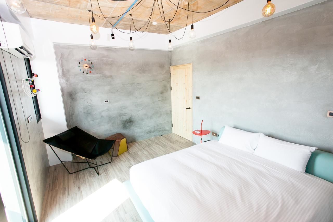 Un dormitorio moderno con una cama grande, una mesita pequeña y una silla.