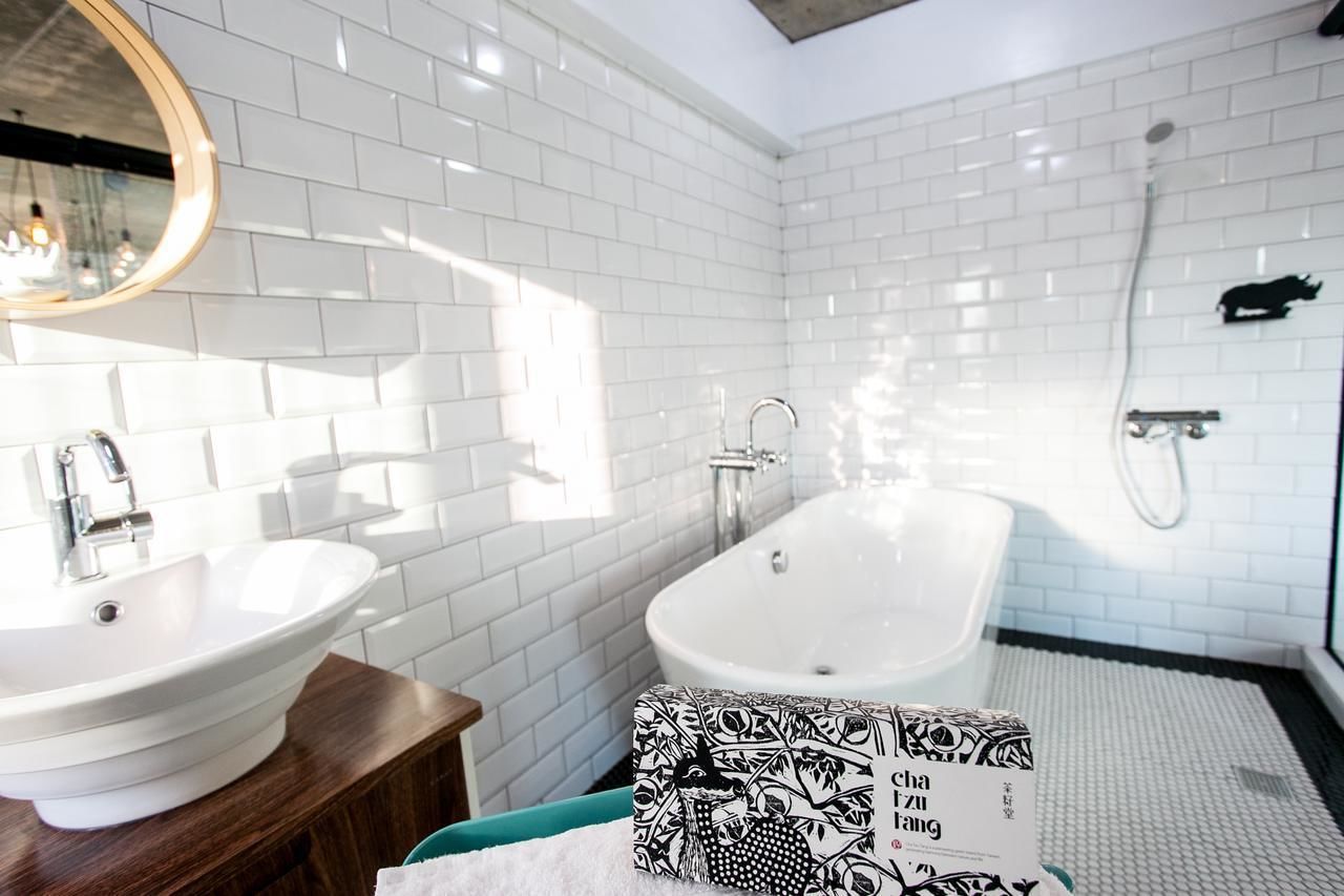 Een moderne badkamer met witte betegelde wanden, een vrijstaand bad, een wastafel en een spiegel.